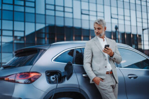 businessman holding smartphone while charging car 2022 11 10 01 07 14 utc scaled