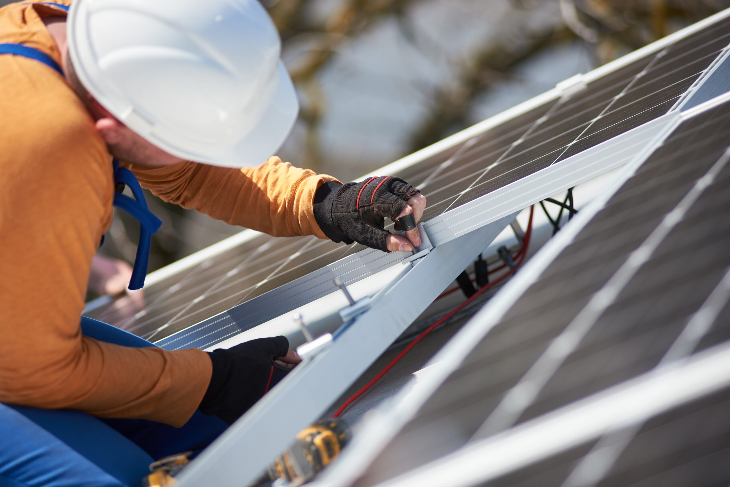 Ein Mann arbeitet an Sonnenkollektoren auf einem Dach.